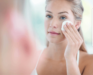 A woman is looking at her face in the mirror